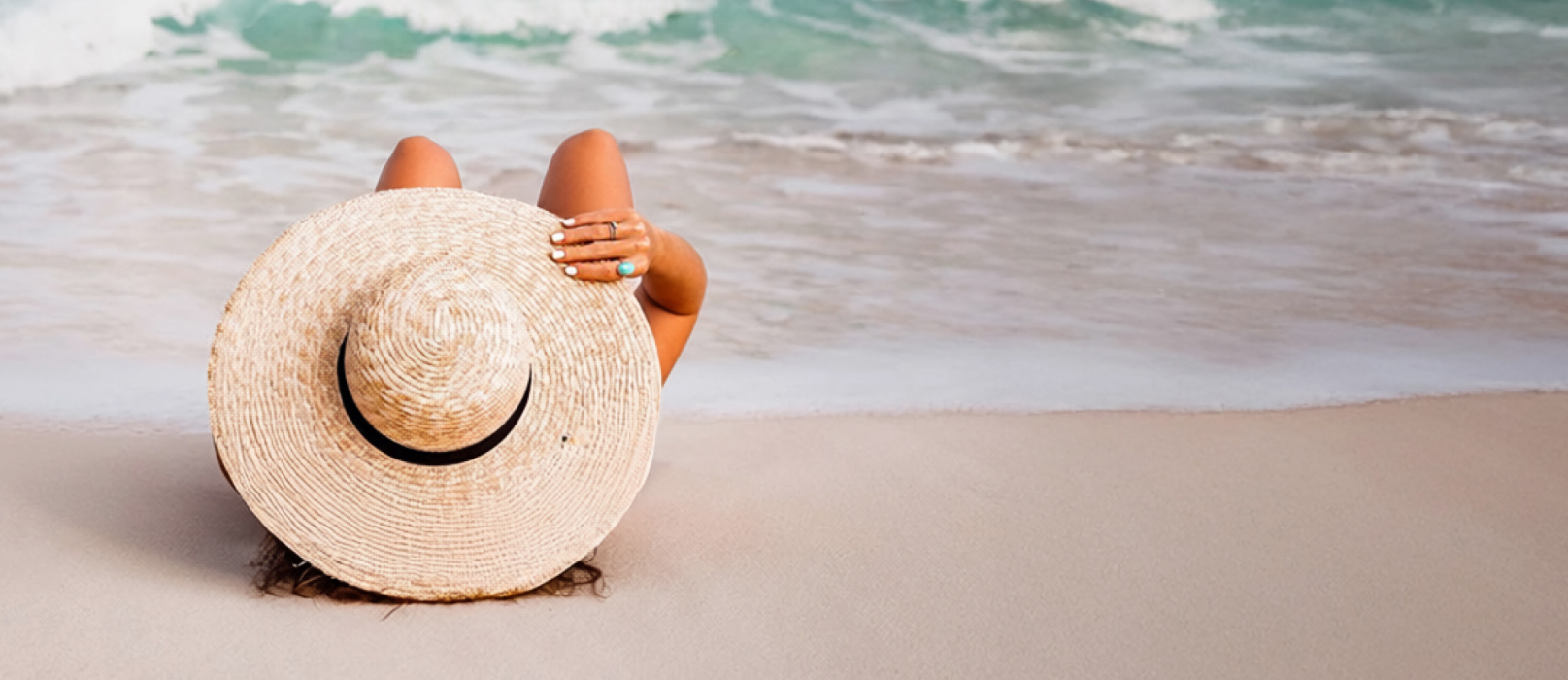 Une femme allong&eacute;e sur la plage portant un chapeau de soleil. 